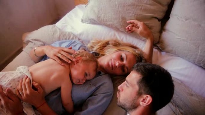 充满爱心的父母与小儿子在床上放松