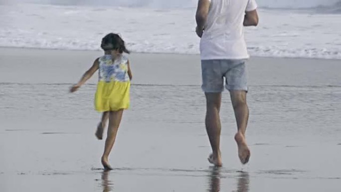 小女孩和爸爸一起跑向海洋
