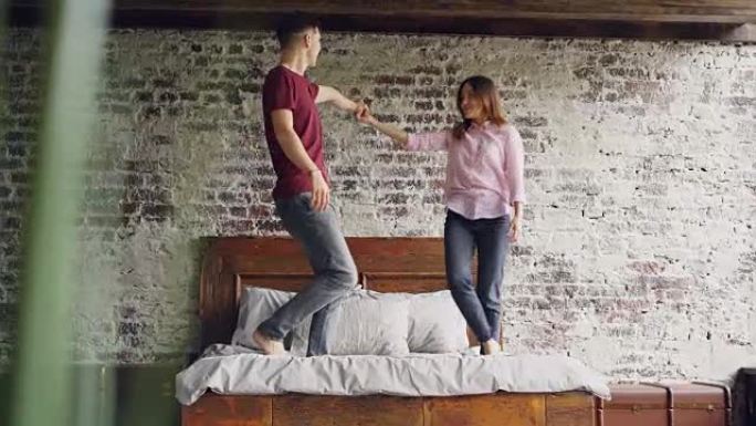 年轻的女友和男朋友在双人床上跳舞，亲吻在卧室里一起玩乐。快乐活跃的人，浪漫的关系和爱情概念。