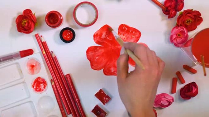 女艺术家手画红花。创意艺术家办公桌从上面。