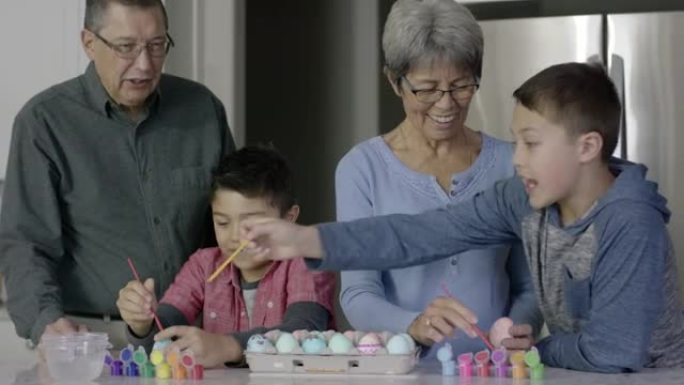 民族祖父母与两个年轻的孙子一起画复活节彩蛋