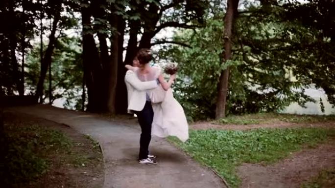 公园里时尚的新娘和新郎。新郎抱着新娘，四处打转。快乐的恋人分享婚礼当天