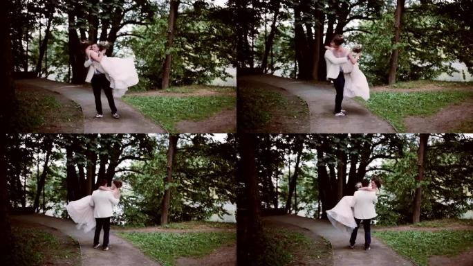 公园里时尚的新娘和新郎。新郎抱着新娘，四处打转。快乐的恋人分享婚礼当天