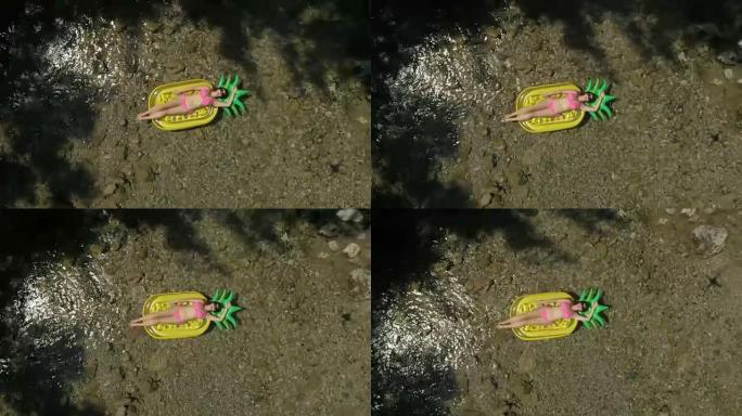 空中: 年轻的游客在菠萝形漂浮物上沐浴着太阳