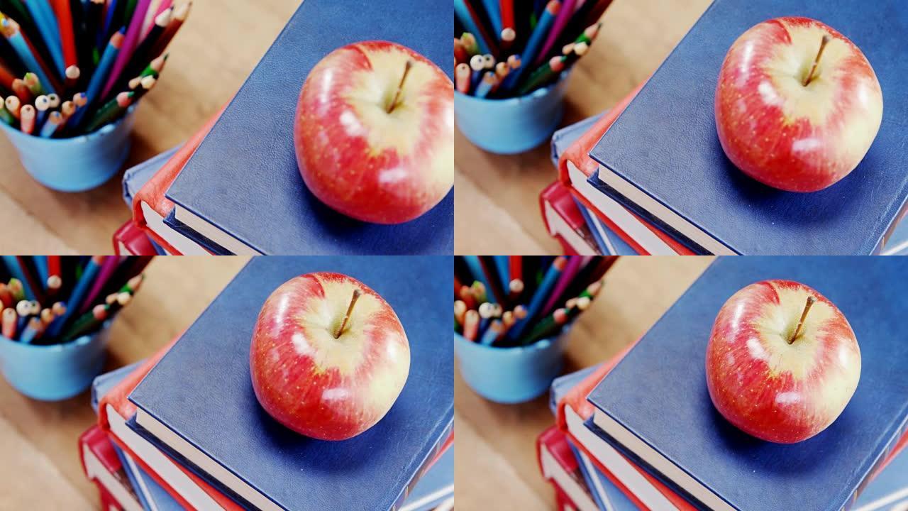 桌子上有铅笔架的苹果书堆