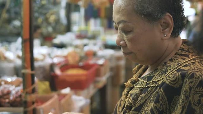 高级妇女正在曼谷/中国城购买食物