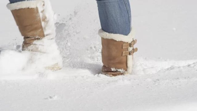 特写: 无法识别的女孩穿着冬靴走在新鲜的未触及的雪中