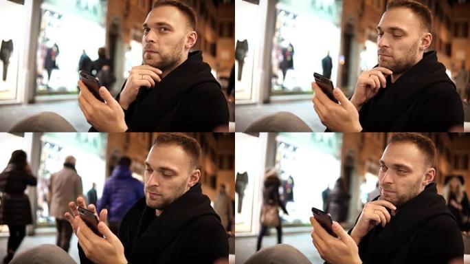 留着胡须的年轻英俊男子坐在咖啡馆里，在市中心度过闲暇时光，并使用智能手机