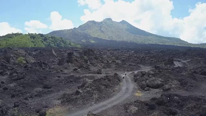 空中: 游客在巴厘岛金塔马尼火山的黑色熔岩路径上骑着踏板车