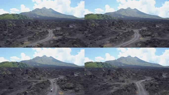 空中: 游客在巴厘岛金塔马尼火山的黑色熔岩路径上骑着踏板车