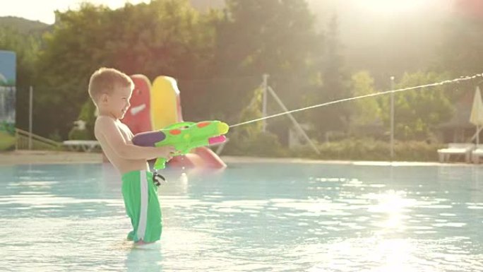 慢动作: 快乐的小男孩在aquapark美丽的夏日日落时用水枪打架
