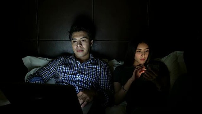 年轻夫妇背靠背坐在家里使用笔记本电脑和手机，网络成瘾，网上购物，忽视和痴迷，不说话，关系中的问题概念