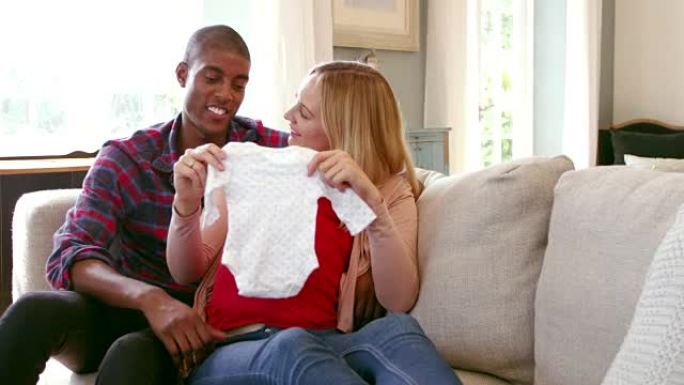 怀孕的夫妇在家中穿着R3D拍摄的婴儿衣服