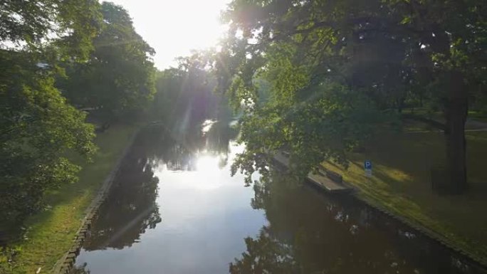 拉脱维亚公园和里加运河的万向节稳定跟踪镜头。温暖的阳光透过树叶照射。4K, UHD