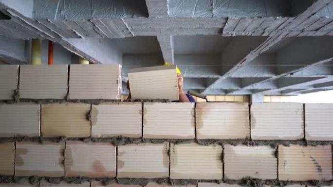 中年建筑工人建造一堵墙，并在上面放混凝土砖