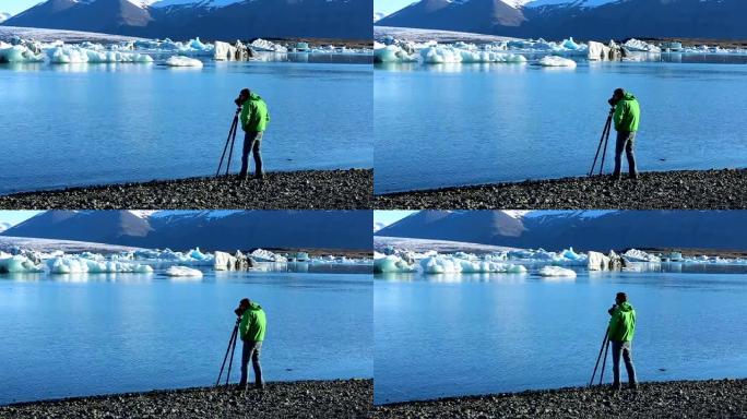 年轻人在三脚架上使用相机拍摄冰山照片。