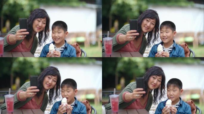 妈妈和孩子在户外咖啡馆用智能手机拍照