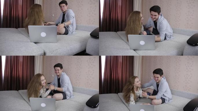 幸福的微笑夫妇使用笔记本电脑坐在家里的沙发上