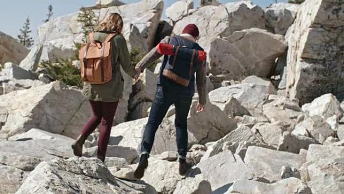 夫妇在徒步旅行中小心翼翼地踩在岩石上