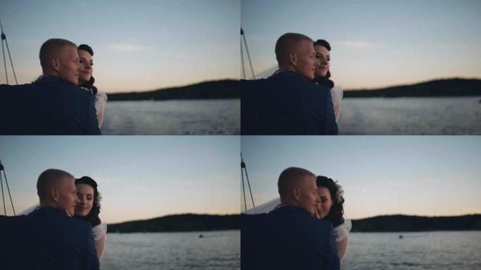 结婚后，幸福的新婚夫妇在日落时在游艇上航行。新娘和新郎在大自然上的浪漫时光