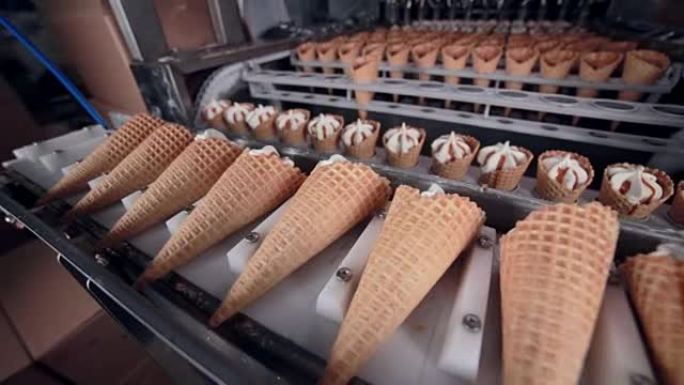 机器将准备好的冰淇淋蛋筒放在传送带上。高清。