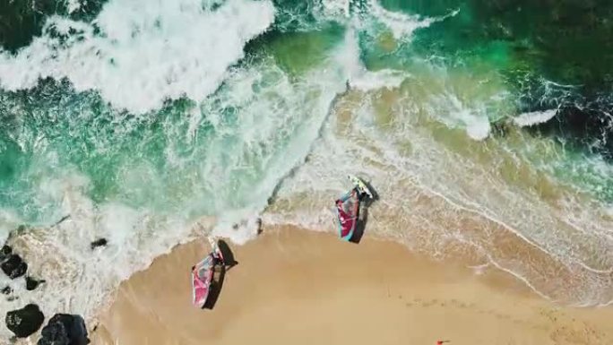 风帆冲浪者从白色沙滩驶入蓝色海洋的鸟瞰图