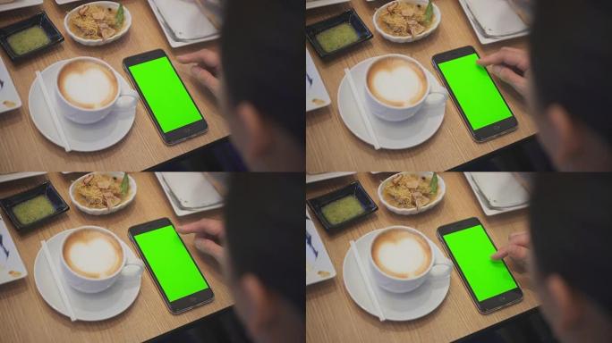 在餐厅使用智能手机的肩膀拍摄，绿屏