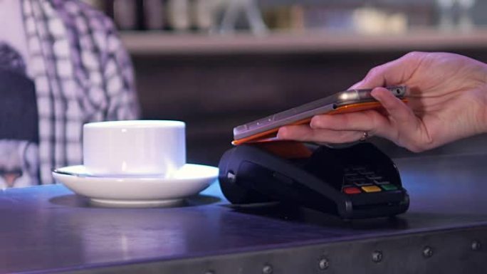 在咖啡馆使用终端和电话进行无线支付的人。4K。