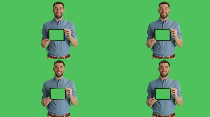 一个微笑的人在展示带有绿色屏幕的水平平板电脑时的中间镜头。背景中的绿色屏幕。