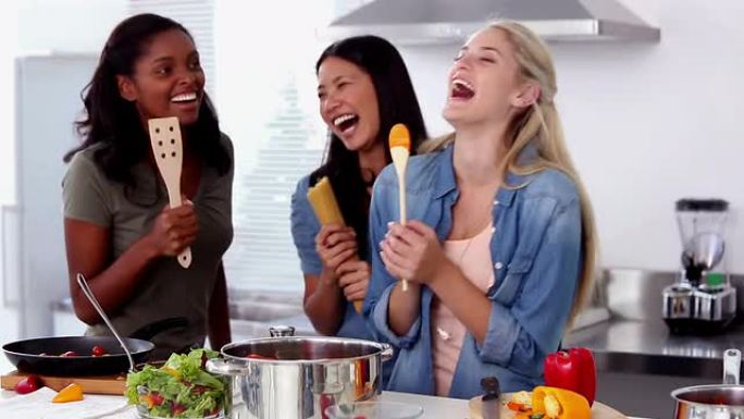 笑着的朋友在做饭时唱歌成木勺