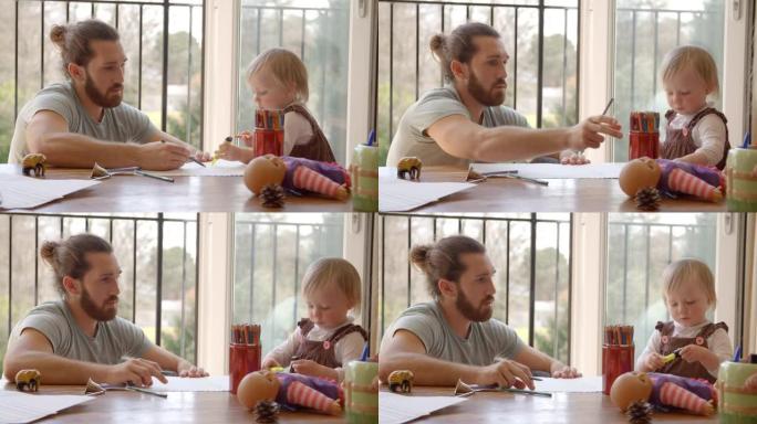 父亲和女儿坐在桌子旁画画