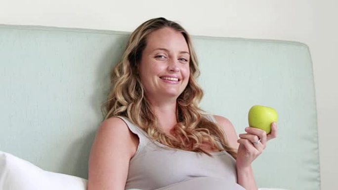 孕妇拿着苹果对着镜头微笑