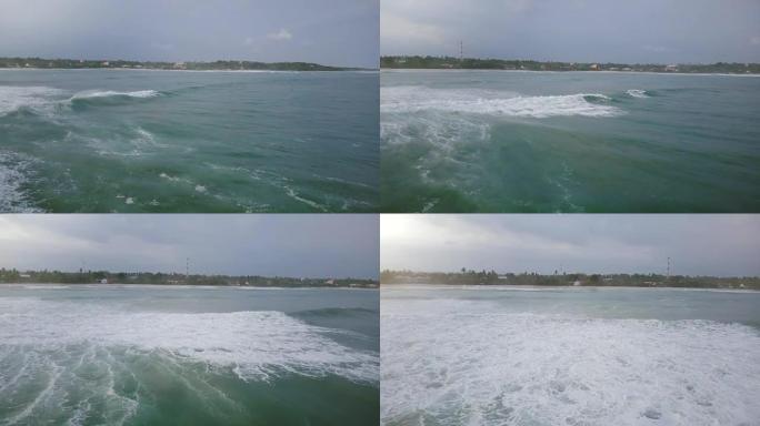 无人机摄像机左转，跟随巨大的海浪到达宁静的热带海滩，并用美丽的泡沫坠毁
