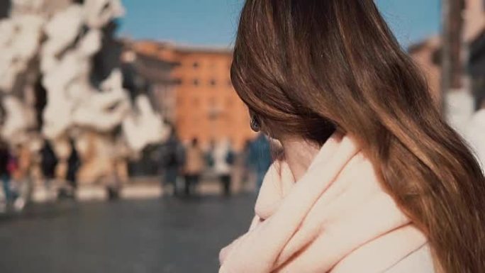 年轻迷人的女人坐在纳沃纳广场，环顾四周。在意大利罗马享受阳光明媚的日子的女孩