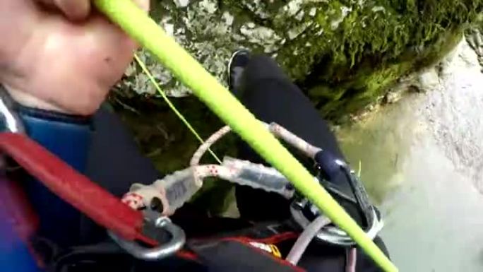 FPV: 人用绳索下降陡峭的苔藓山墙，跳入河中