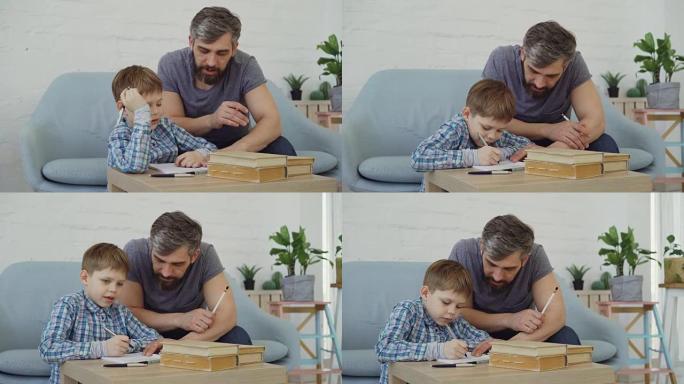 细心的父亲中年大胡子男人正在帮助儿子专心的男孩做功课。当他的父亲说话和检查时，孩子正在写练习本。