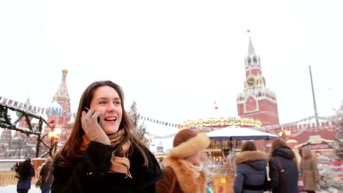 冬天，女人站在莫斯科红场，克里姆林宫和圣巴西尔大教堂前的电话里