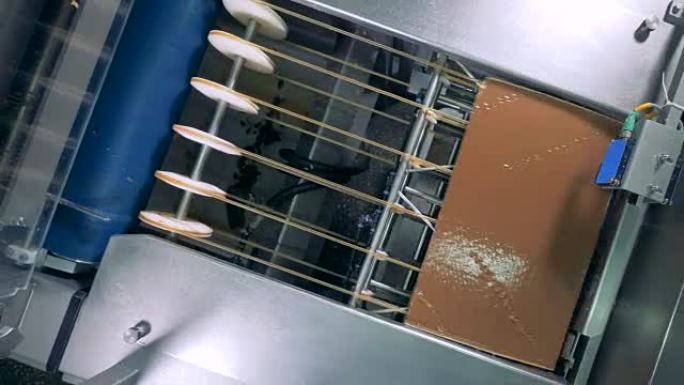 面团在传送带上移动，切成薄片并覆盖巧克力。