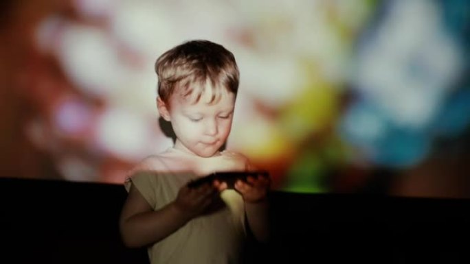 小男孩在聚光灯下用智能手机跳舞