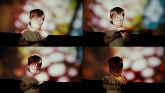 小男孩在聚光灯下用智能手机跳舞