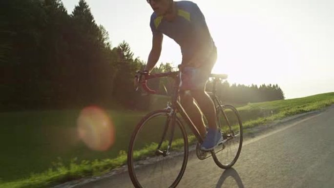 太阳耀斑职业自行车手在美丽的夏日夜晚轻松超越移动相机