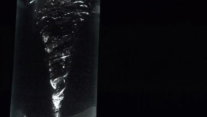 黑色背景上的杯水中的漩涡