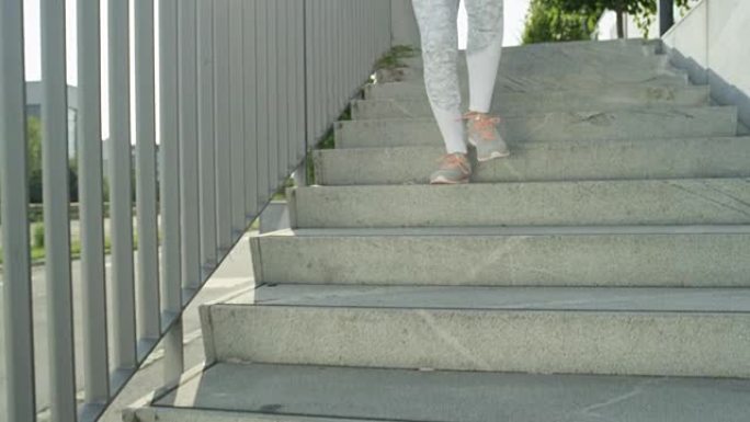慢动作: 穿着白色衣服的未知健康女孩早上从水泥楼梯上跑下来。
