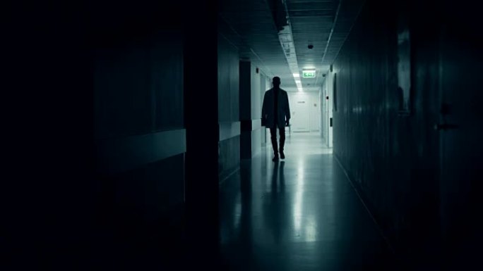 医生走进医院走廊的黑暗部分。