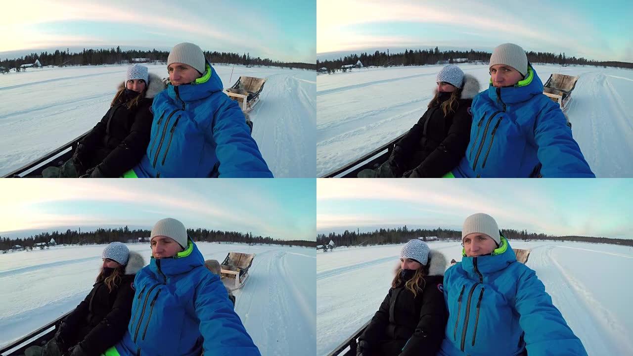 肖像: 情侣骑着驯鹿雪橇在白雪皑皑的拉普兰旅游景点