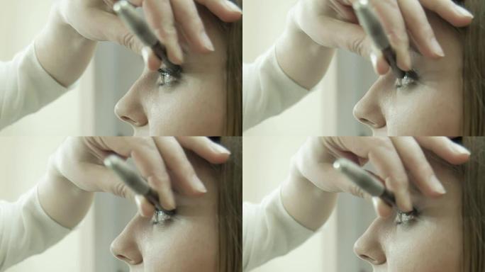 化妆师在眼睑上涂眼线笔。