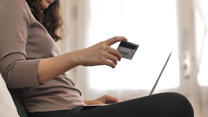 年轻女子用信用卡和笔记本电脑在线支付账单