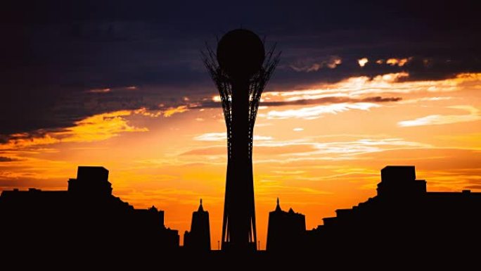 在美丽的日落时，哈萨克斯坦首都阿斯塔纳的剪影Bayterek塔的延时