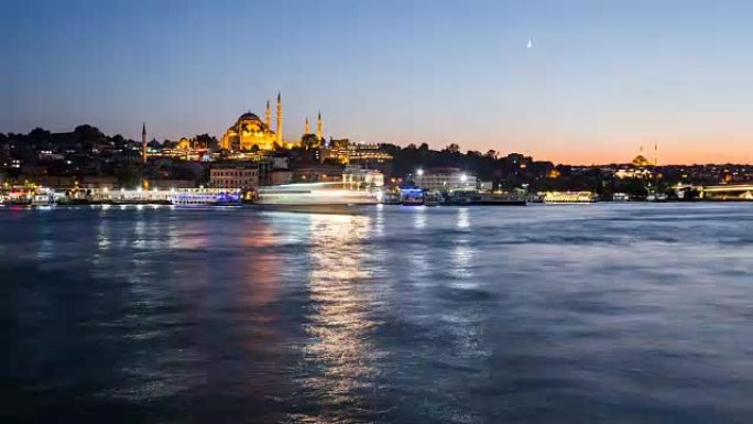 伊斯坦布尔城市景观的时光倒流与苏莱曼清真寺，旅游船在夜间漂浮在博斯普鲁斯海峡