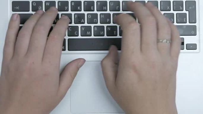 男性手使用的笔记本电脑键盘和触摸板的俯视图。特写